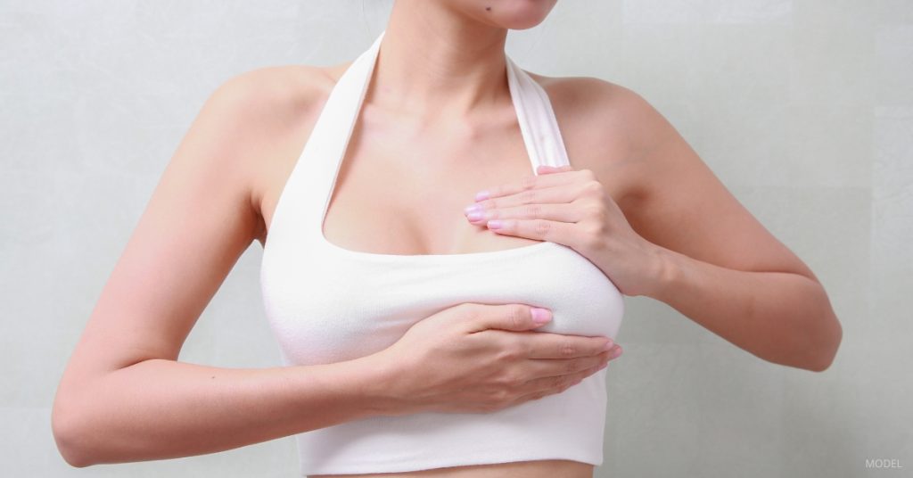 Young woman experiencing chest tightness after breast augmentation (MODEL)